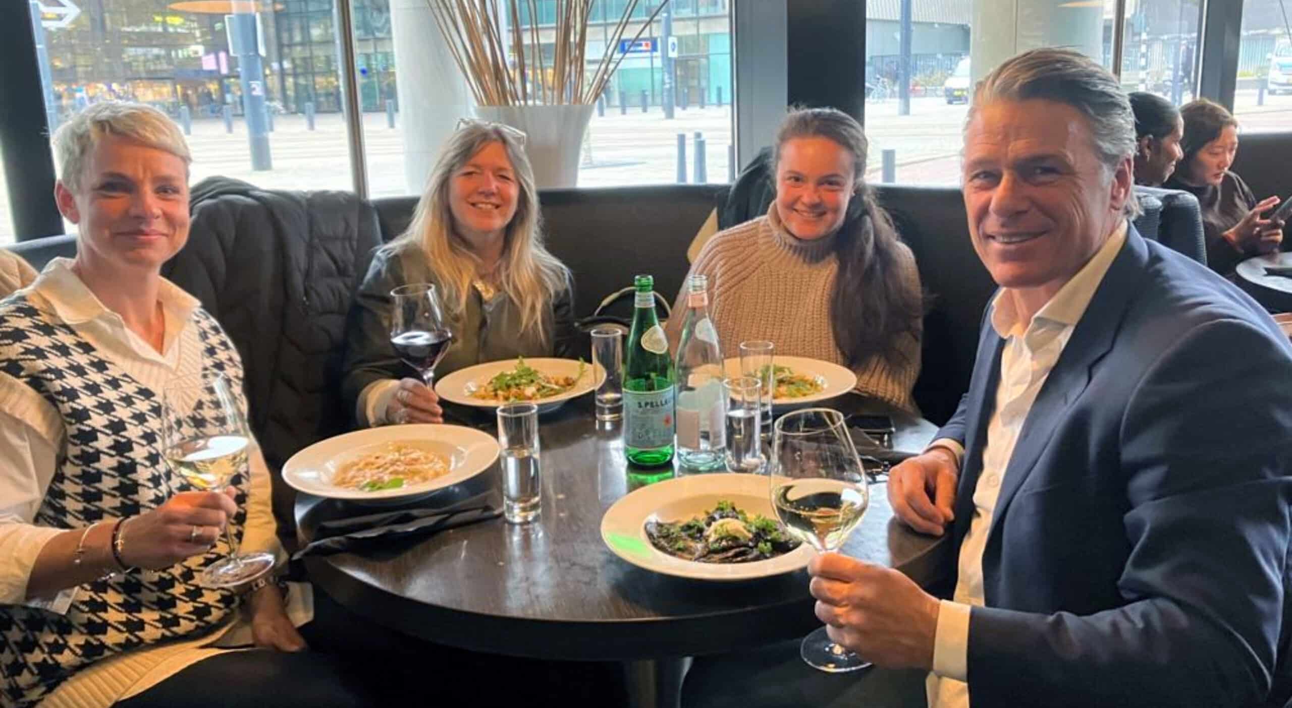 Four people dining together at a restaurant with wine